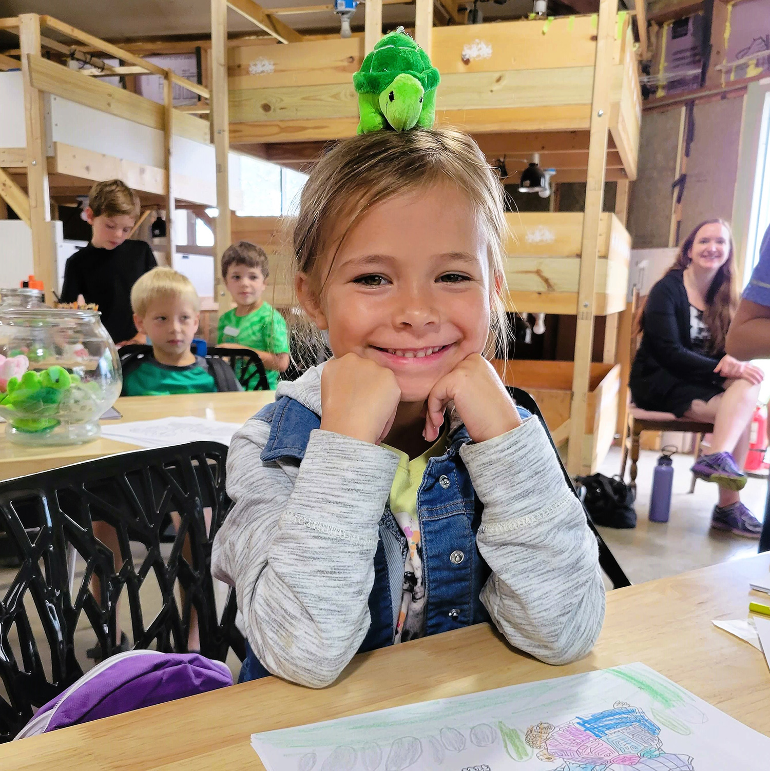 a smiling girl with a small turtle toy on her head